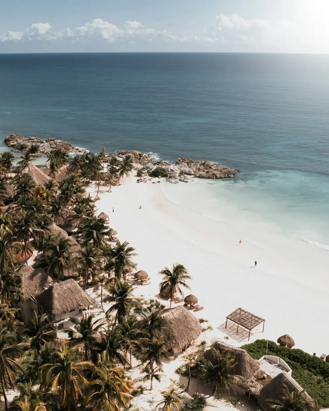 An elevated view over a palm-lined white-sand Caribbean cove